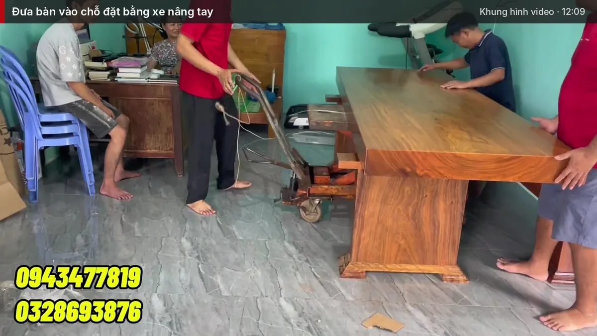 Nhiều người cùng đỡ mặt bàn, kê lên xe nâng tay đưa vào chỗ đặt Nhiều người cùng đỡ mặt bàn, kê lên xe nâng tay đưa vào chỗ đặt